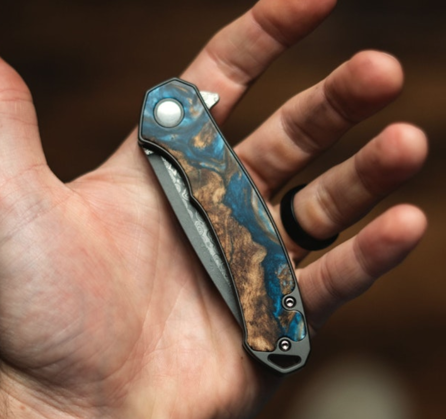 A hand holding a pocket knife in the palm.